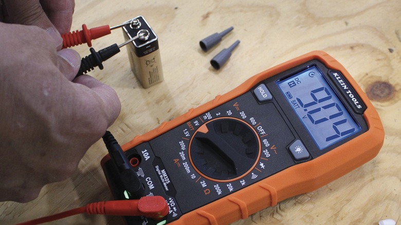 Using the Klein Tool MM325 manual ranging multimeter to test the voltage of a 9-volt battery.