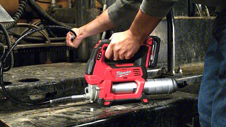 Person using cordless Milwaukee grease gun