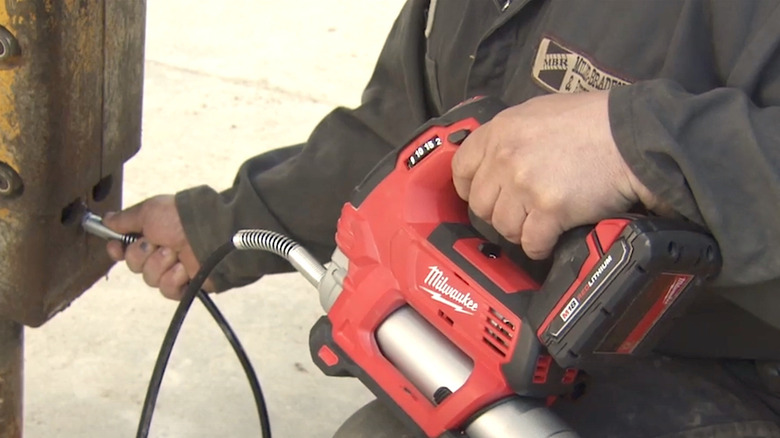 Person using cordless Milwaukee grease gun
