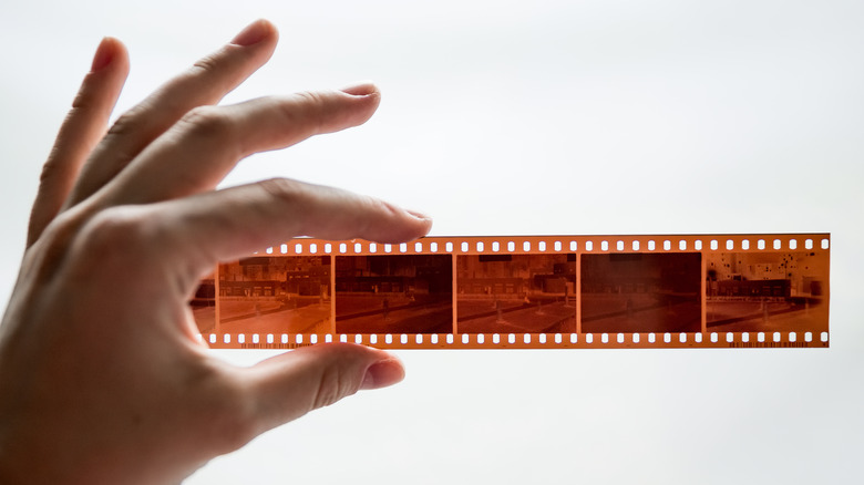 Hand holding up film negatives in front of light background