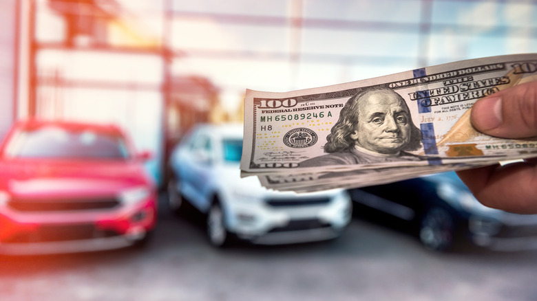 Hundred dollar bills in front of cars