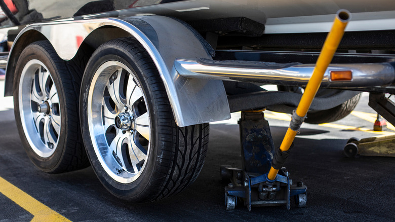 A trolley jack sits under a four-wheeled trailer.