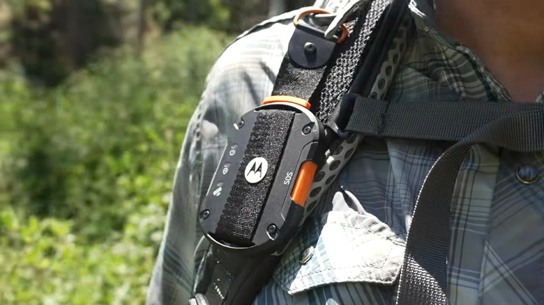 A Motorola Defy Satellite Link strapped onto a backpack, showing the orange SOS button.