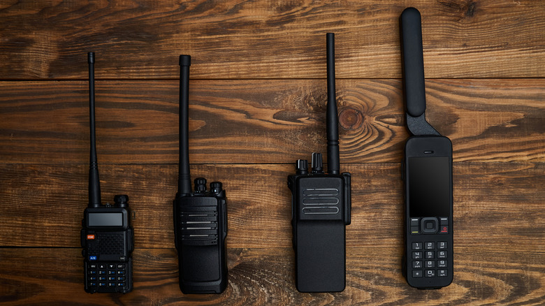 Four black satellite phones on a table side-by-side.