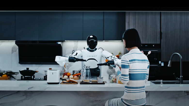 An Agibot humanoid robot helping a woman perform cooking tasks in a kitchen.