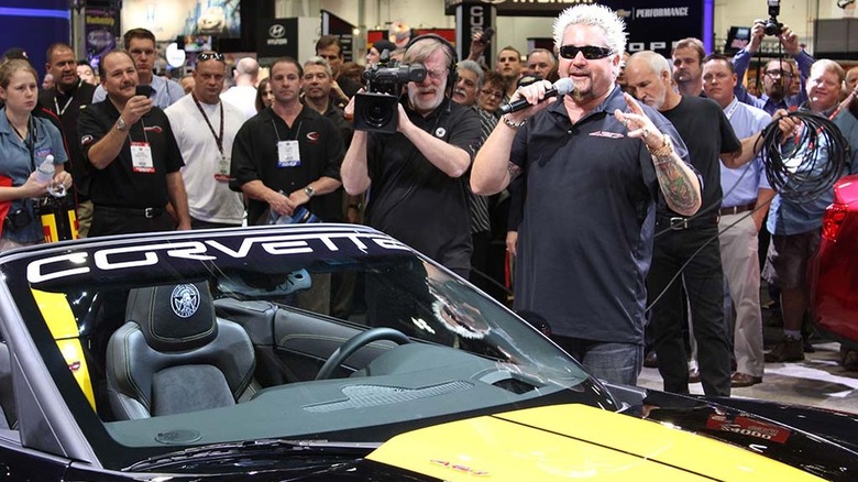 Guy Fieri standing next to his black and yellow Corvette 427