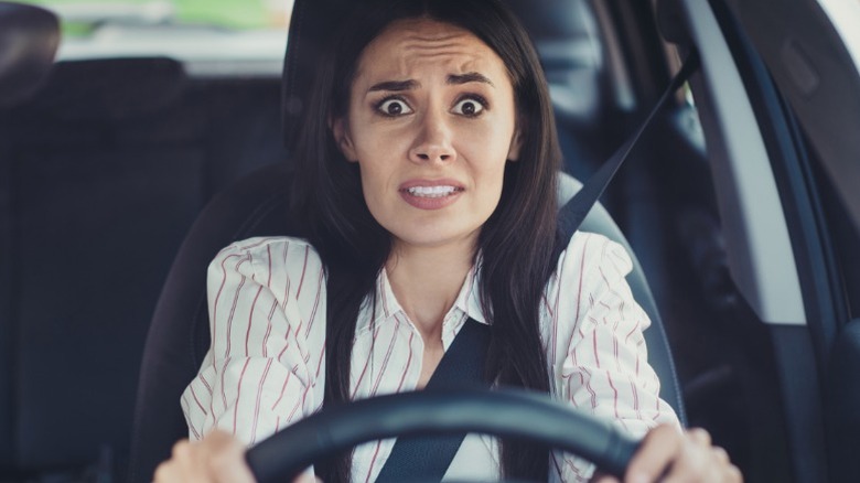 A frightened looking person driving a car