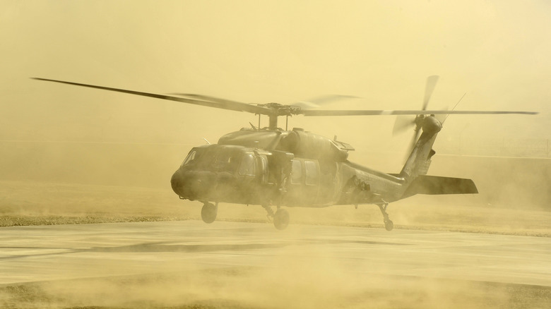 Black Hawk helicopter hovering while surrounded by cloud of sand