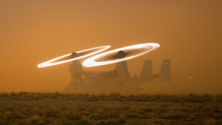 MV-22 Osprey in a sandstorm with the tips of the rotor blades lighting up