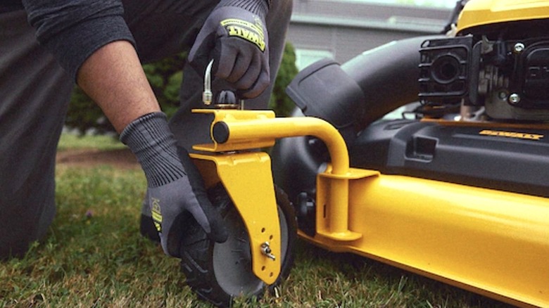 Person checking wheels of DeWalt's 28-inch 3-in-1 Lawn Mower