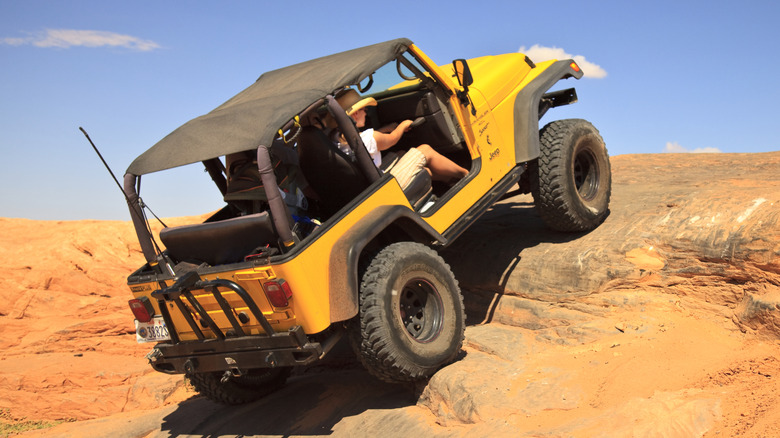 A yellow Jeep tackles tough off-road terrain