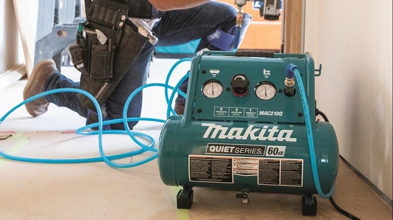 A Man Using A Makita Portable Electric Compressor With A Nailer