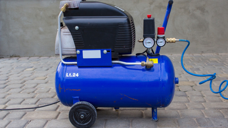 A Blue Electric Air Compressor On Pavers With Gray Background