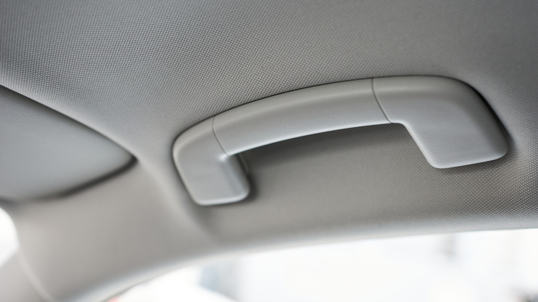A close-up image of a light-colored car grab handle above the door.