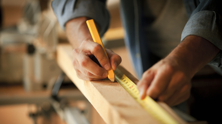 Person marking wood with tape measure