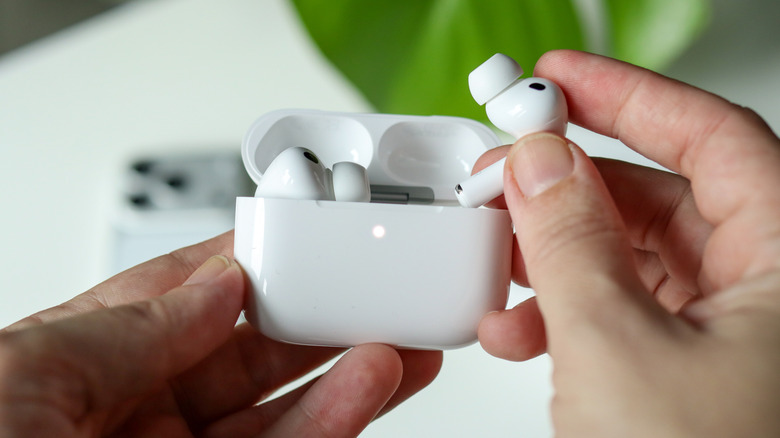 Person's hands placing an AirPod Pro back into its case.