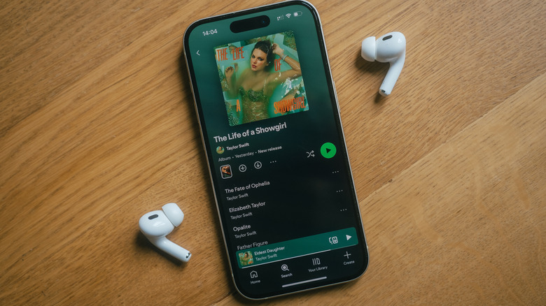 AirPods Pro wireless headphones on either side of an iPhone open to Spotify.