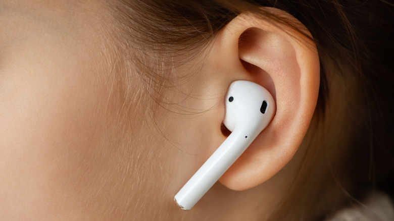 Person wearing a wireless headphone in their ear.