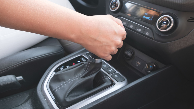 A person driving a manual car with their hand on the shifter