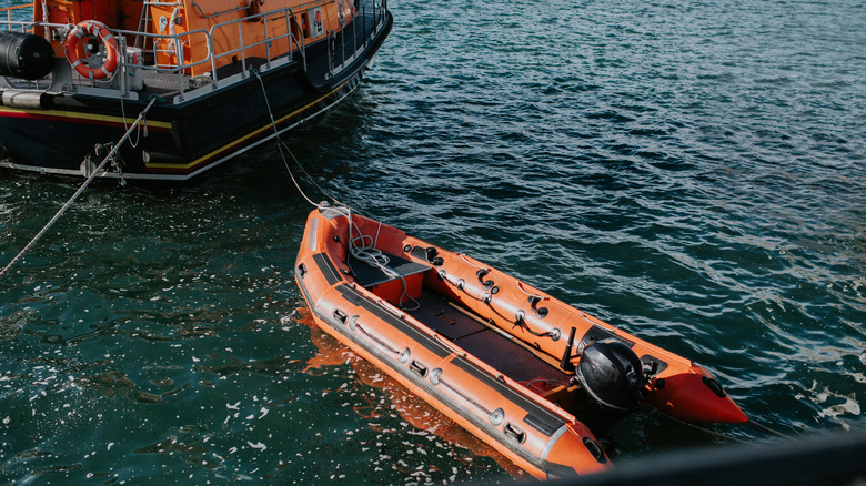 A smaller motorised speedboat is attached to a large rescue vessel.