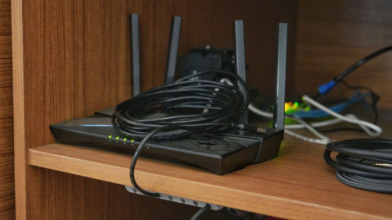 A Wi-Fi router installed on a wooden table that is situated in a corner.