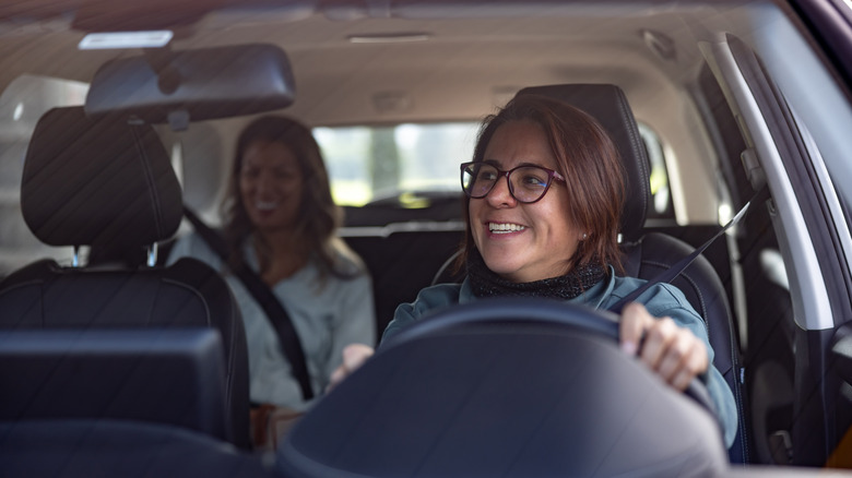 A female driver talks to a female passenger in the back seat