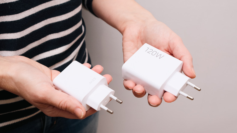 Person holding two USB charging bricks