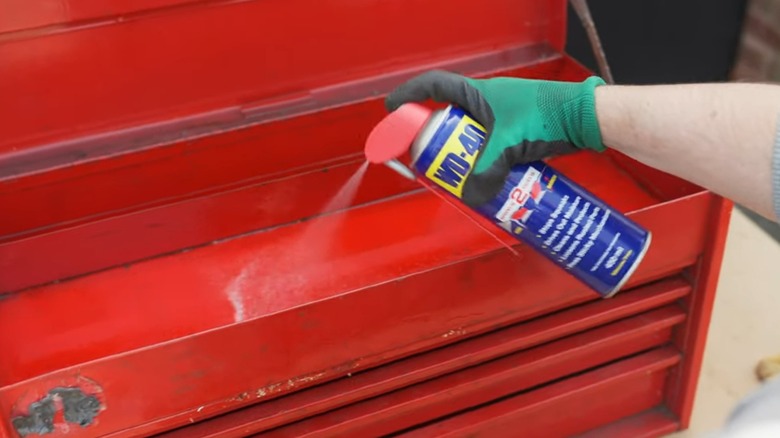 A person cleaning a toolbox with WD-40