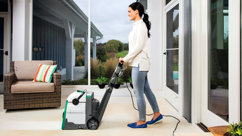 A woman using a carpet cleaner on a beige carpet