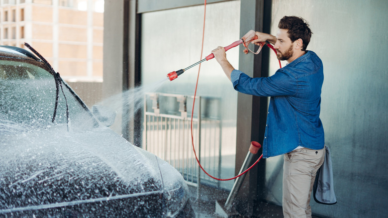 man pressure washing car