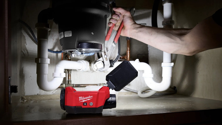 Person using Milwaukee packout light under a sink