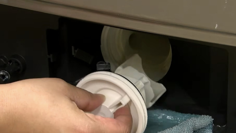 A close-up of a hand removing a drain filter