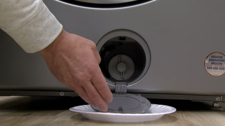 A close-up of a hand opening a drain pump access door