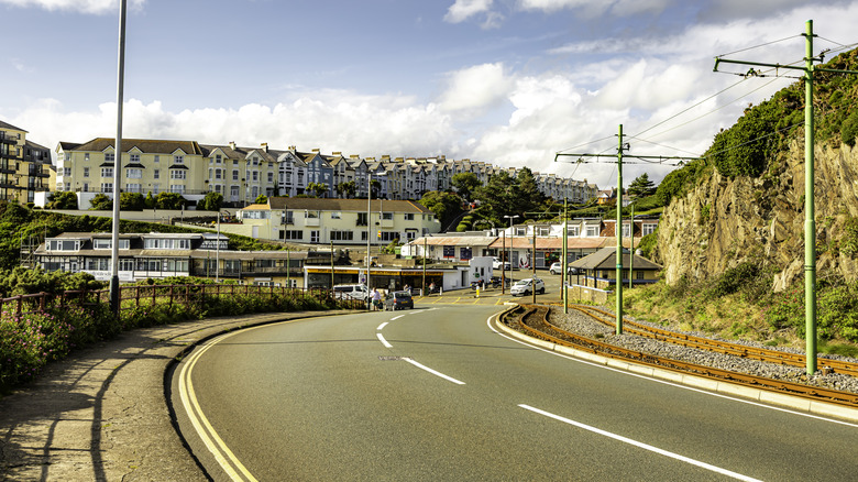 Winding road on the Isle of Man with houses and apartments in the distance.