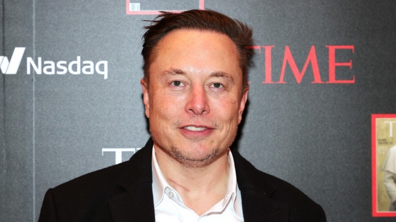 Elon Musk in front of TIME and Nasdaq logos