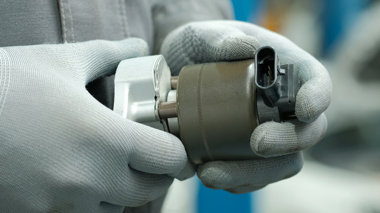gloved hands holding EGR valve