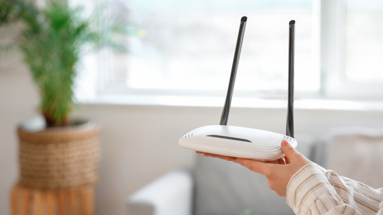 Hands holding up a white router