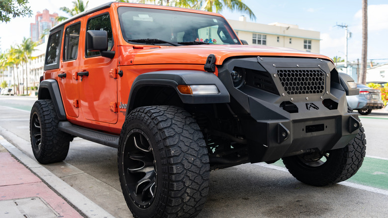 A modified orange Jeep Wrangler with wide tires and wider fender flares