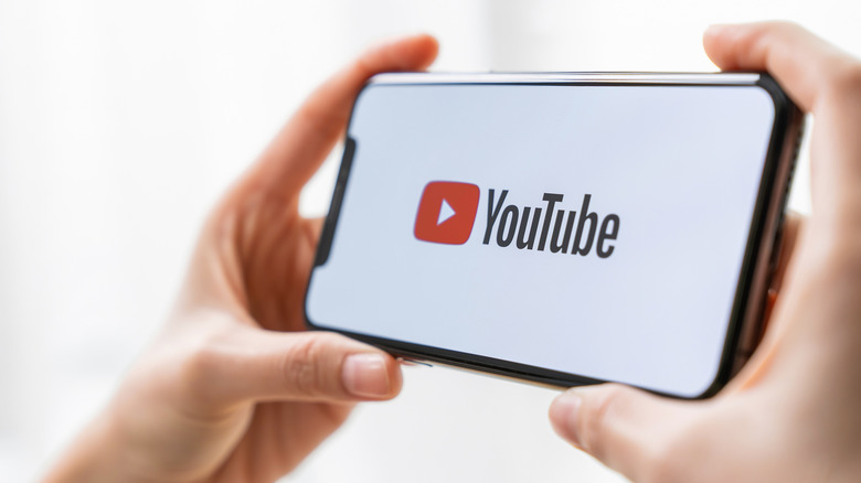 hand holding a phone with YouTube logo