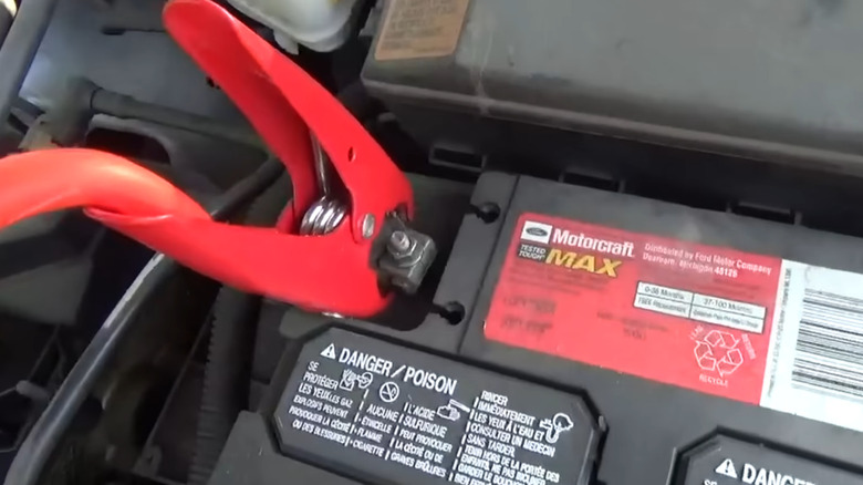 positive jumper cable line hooked up to positive car battery terminal