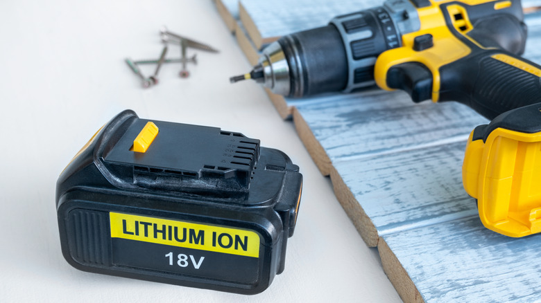 A power tool battery beside a drill.