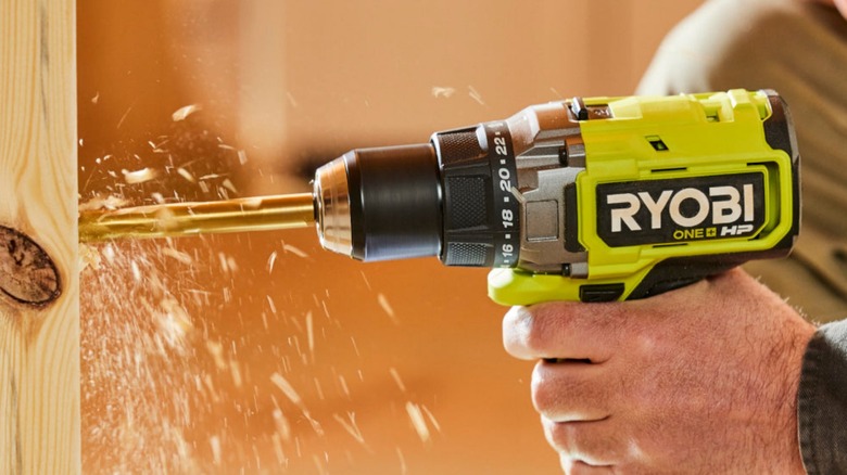 Person drilling into wooden stud with Ryobi drill