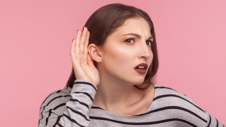 woman holding hand to her ear