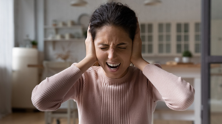 woman covering her ears in pain