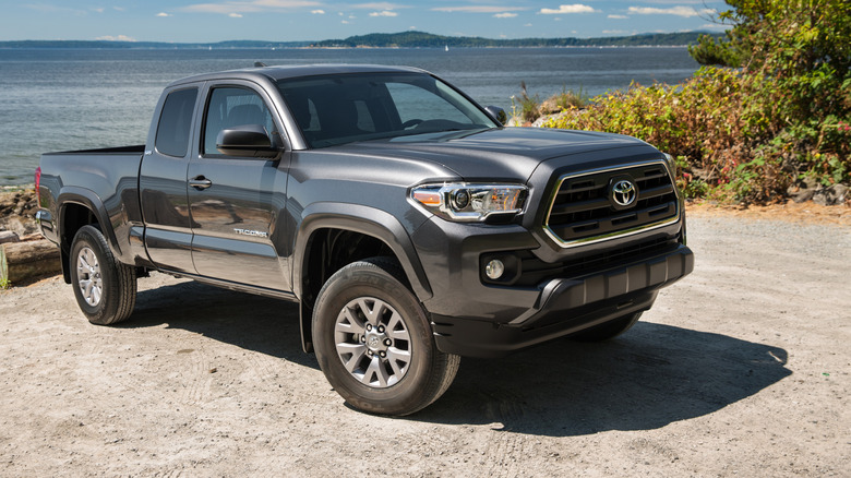 Front three-quarter view of gray 2016 Toyota Tacoma parked next to a lake.