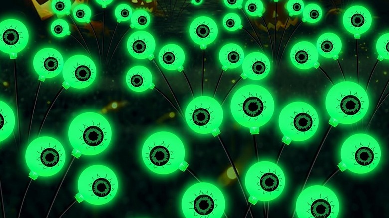 Pairs of green glowing halloween eyes planted in a garden