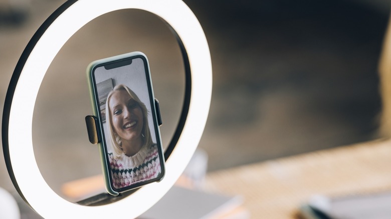 woman smiling on a phone with a ring light