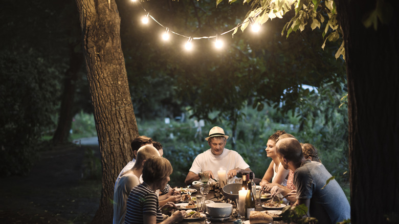 A family having dinner with a set of outdoor lights