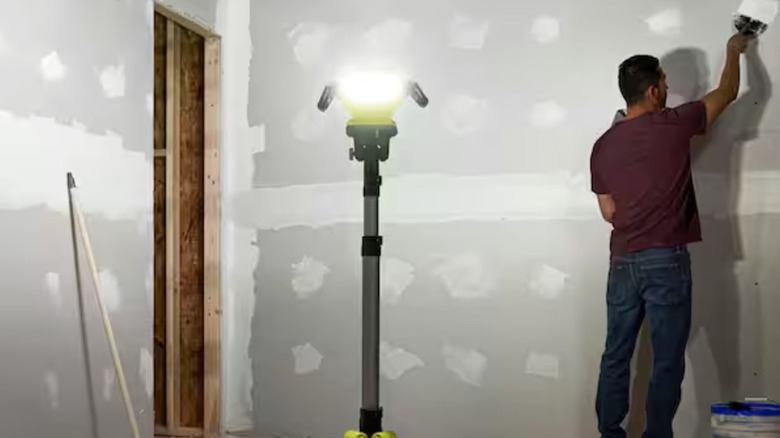 Person using a Ryobi light to paint a room