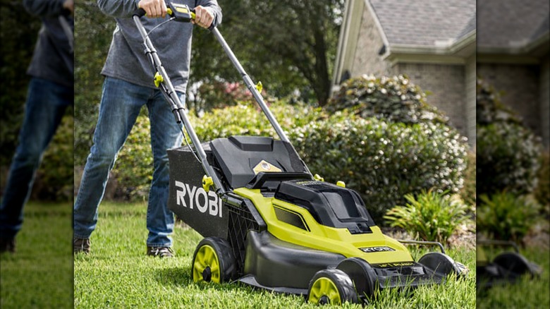 Person using a Ryobi 18V One+ HP 16-inch push mower in a garden